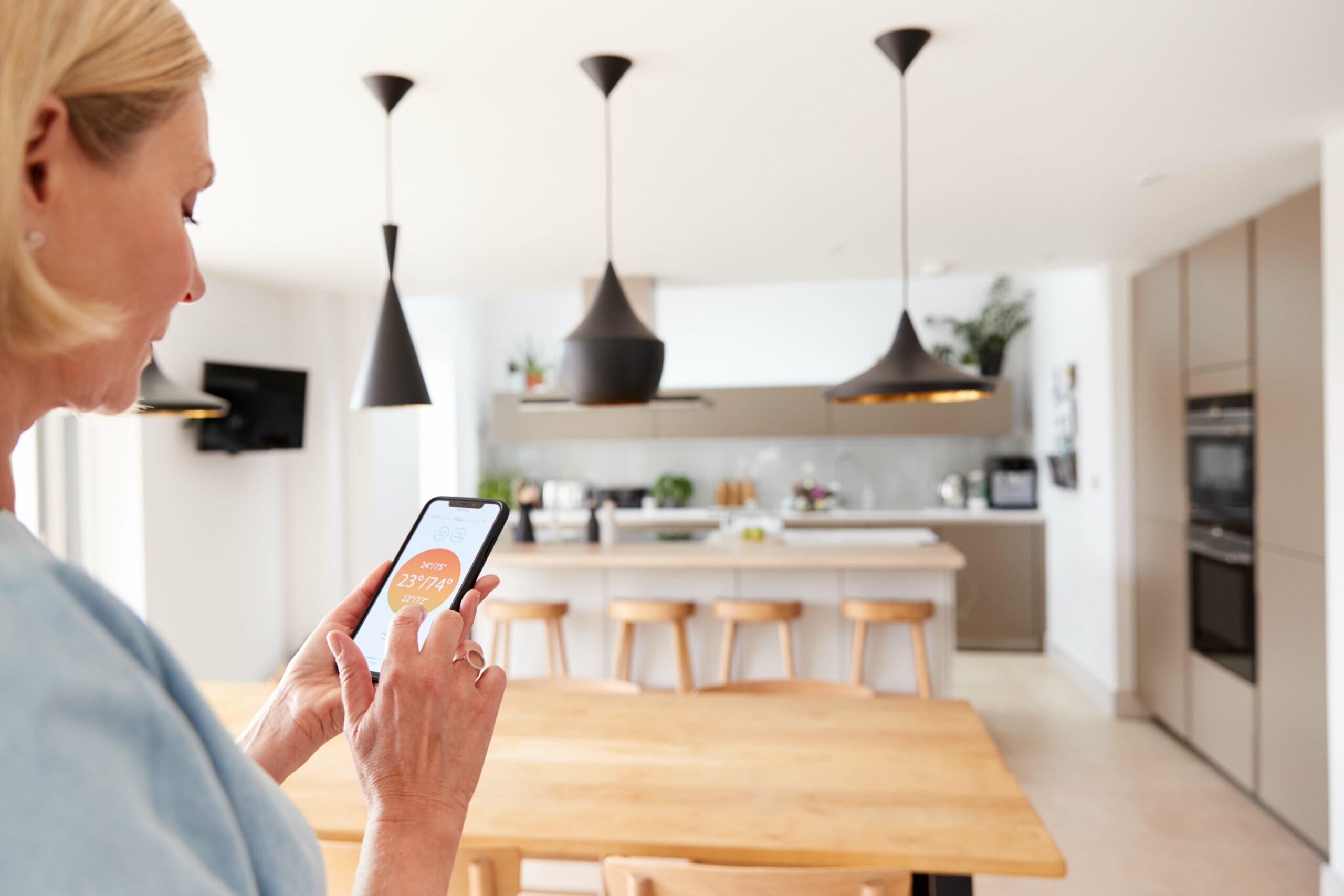 Femme utilisant son téléphone pour régler le thermostat de sa maison